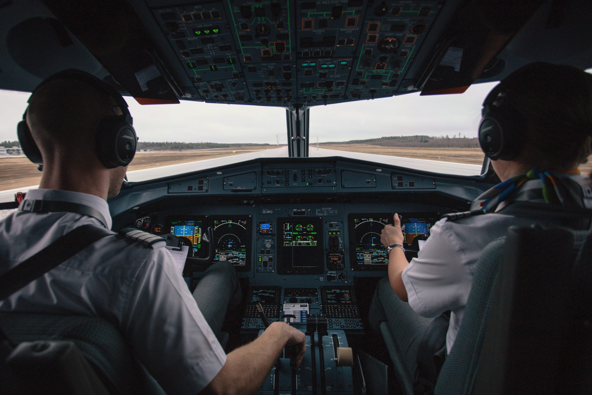 Two pilots sit in a cockpit on the runway preparing for flight.